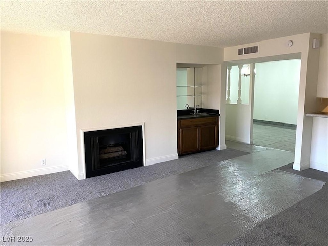 unfurnished living room with a textured ceiling and dark colored carpet