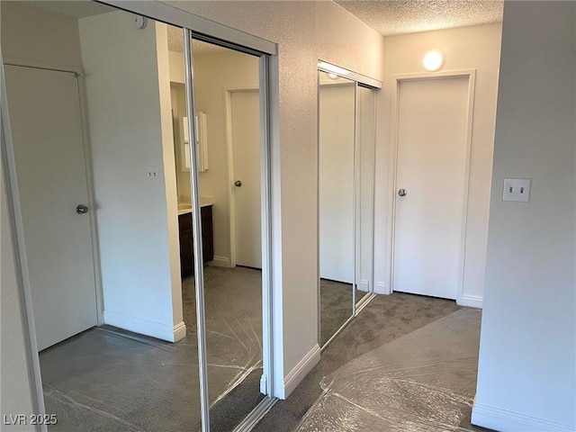 hallway with dark carpet and a textured ceiling