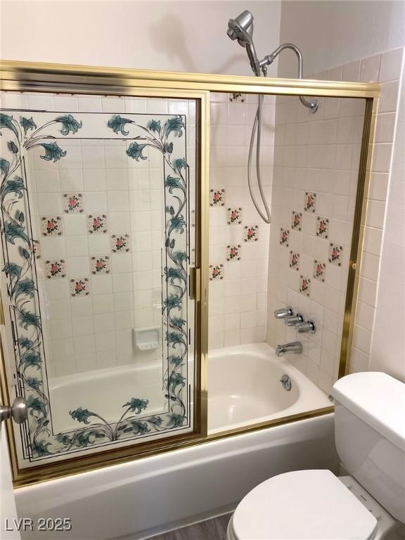 bathroom with toilet and bath / shower combo with glass door