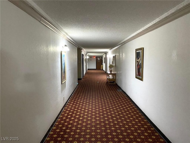 hall featuring dark colored carpet, a textured ceiling, and crown molding