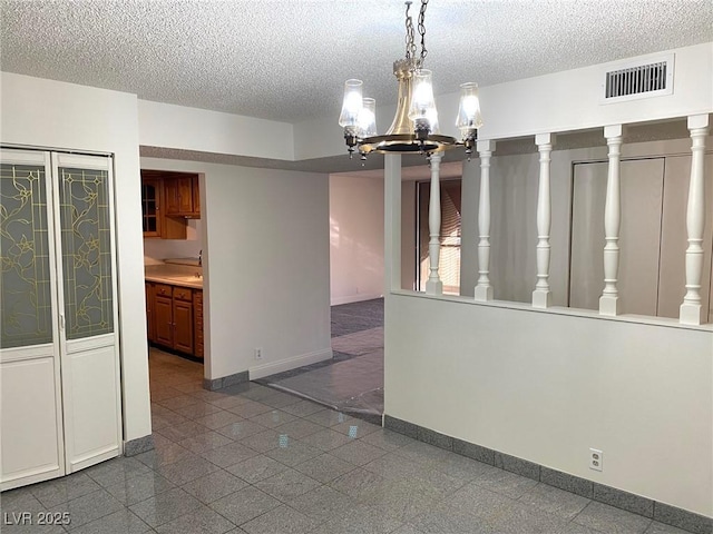 unfurnished dining area with a textured ceiling and a notable chandelier