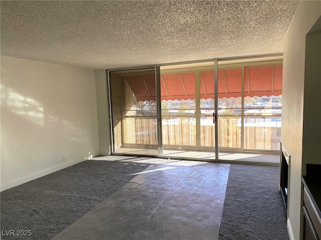 spare room with carpet flooring, floor to ceiling windows, a fireplace, and a textured ceiling