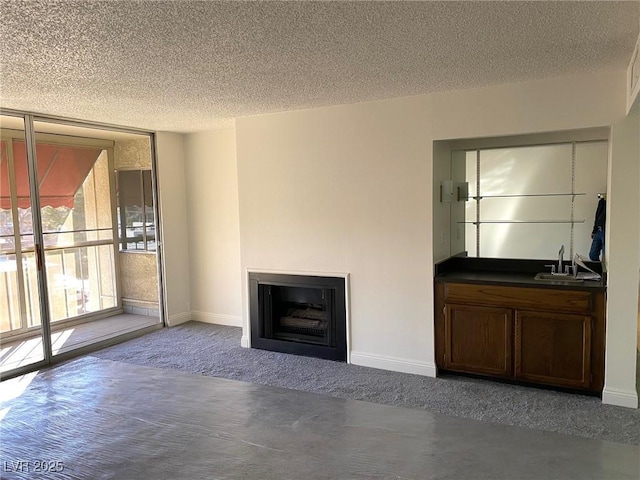 unfurnished living room with a fireplace, sink, carpet floors, and a textured ceiling