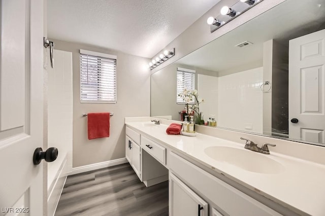 bathroom featuring vanity, hardwood / wood-style floors, a textured ceiling, and a healthy amount of sunlight