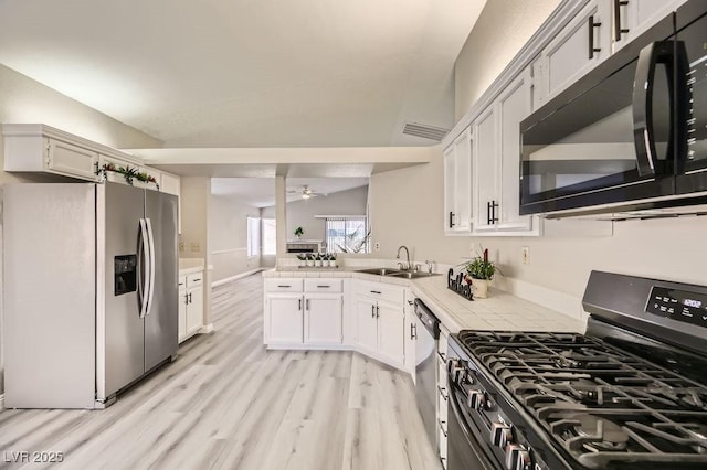 kitchen with sink, white cabinetry, appliances with stainless steel finishes, kitchen peninsula, and light hardwood / wood-style floors