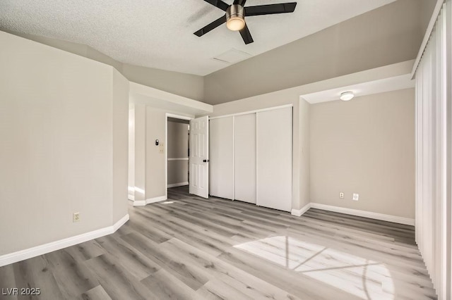 unfurnished bedroom with vaulted ceiling, a closet, ceiling fan, and light wood-type flooring