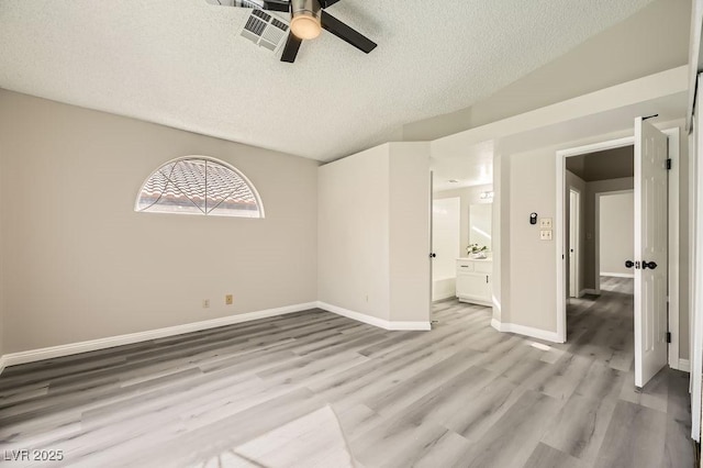 unfurnished room featuring ceiling fan, vaulted ceiling, a textured ceiling, and light hardwood / wood-style floors