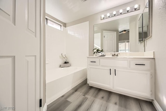 bathroom with hardwood / wood-style flooring, vanity, a bath, and ceiling fan