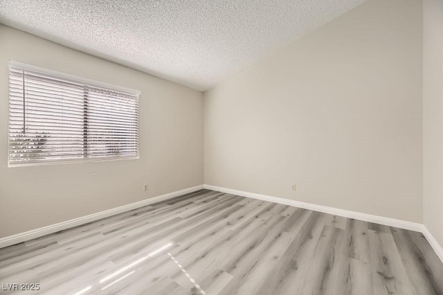 empty room with a textured ceiling and light wood-type flooring