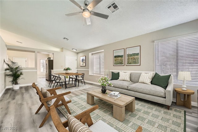 living room with vaulted ceiling, hardwood / wood-style floors, a textured ceiling, and ceiling fan