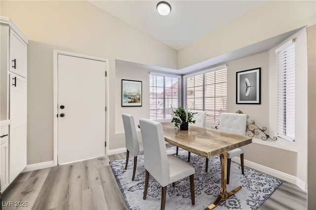 dining room featuring vaulted ceiling and light hardwood / wood-style flooring