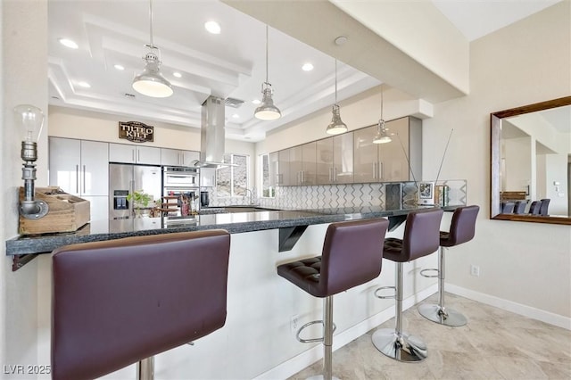 kitchen with gray cabinets, stainless steel fridge with ice dispenser, kitchen peninsula, a kitchen bar, and a tray ceiling