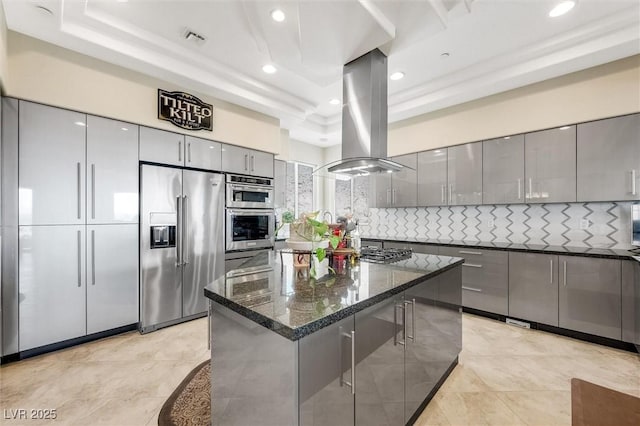 kitchen featuring dark stone countertops, island range hood, gray cabinets, and stainless steel appliances