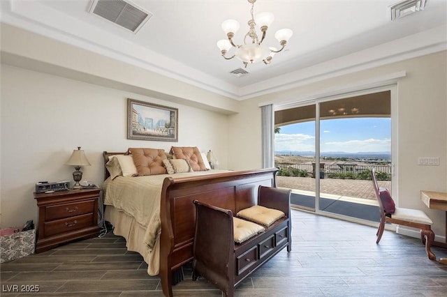 bedroom with a raised ceiling, dark wood-type flooring, access to outside, and an inviting chandelier