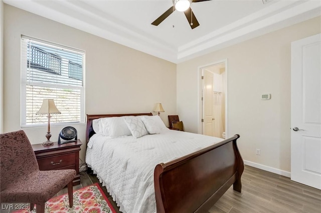 bedroom with ceiling fan, a raised ceiling, and hardwood / wood-style floors