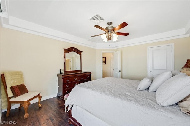 bedroom featuring dark wood-type flooring, ceiling fan, and a tray ceiling