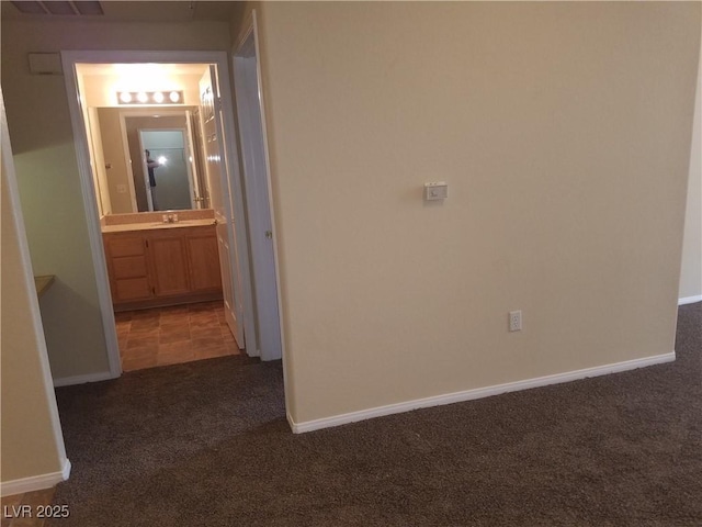 hallway featuring sink and dark carpet