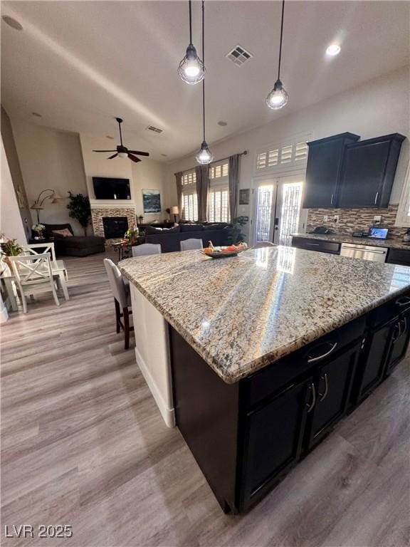 kitchen featuring decorative light fixtures, light wood-type flooring, a center island, and ceiling fan