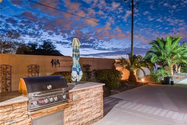 patio terrace at dusk with an outdoor kitchen and grilling area