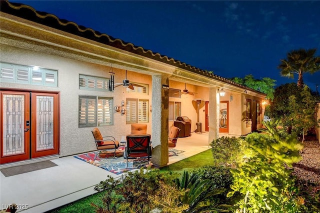 back house at night featuring ceiling fan and a patio area