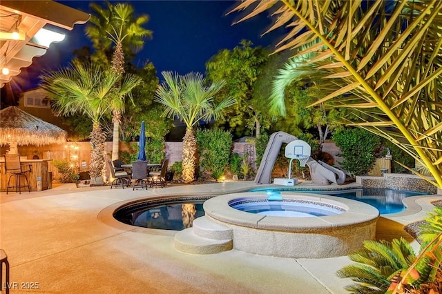 view of swimming pool with exterior bar, an in ground hot tub, a patio, and a water slide