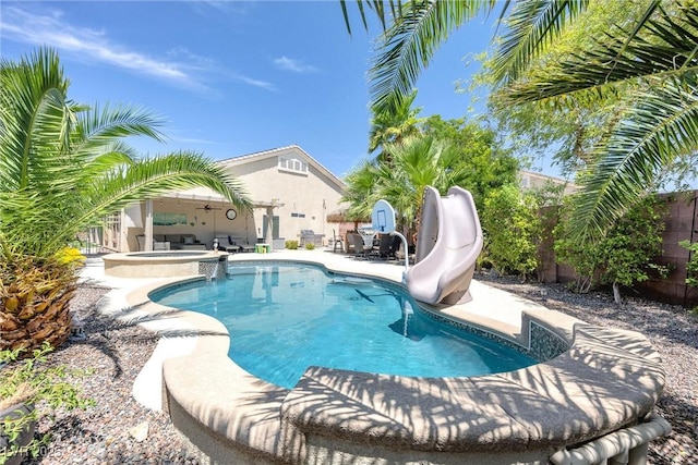 view of pool featuring an in ground hot tub, a patio area, a water slide, and ceiling fan