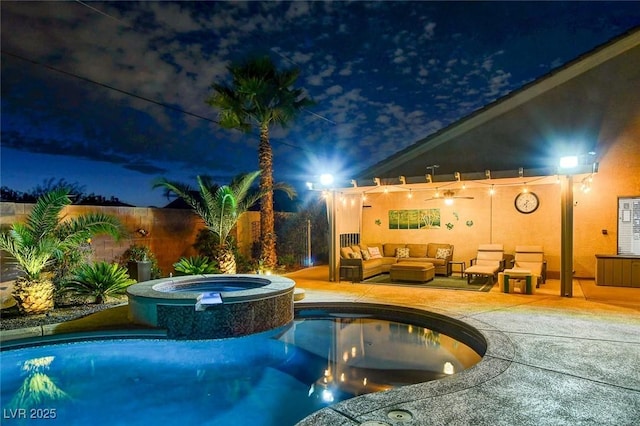 pool at night featuring an in ground hot tub, a patio area, and an outdoor hangout area