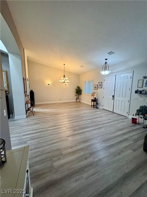 unfurnished living room with light hardwood / wood-style floors and a chandelier