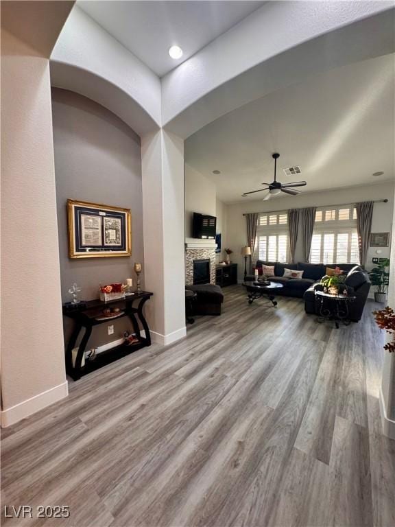 living room featuring ceiling fan, a fireplace, and wood-type flooring