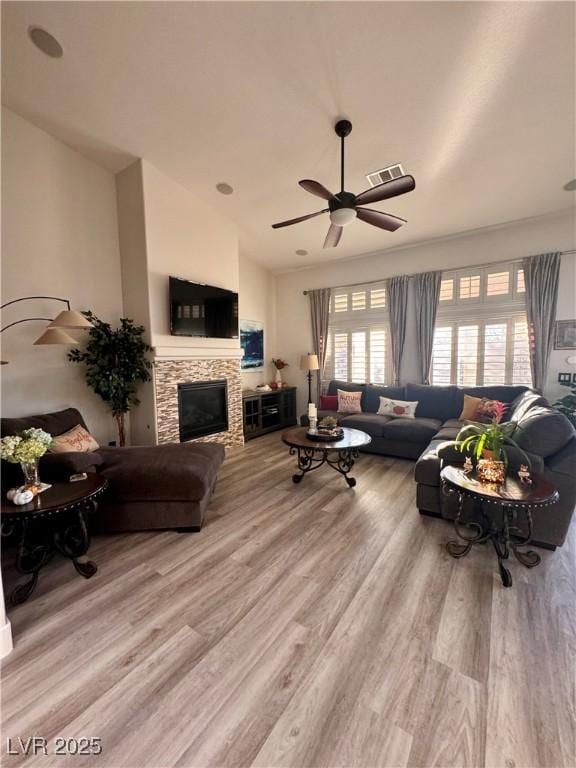 living room featuring light wood-type flooring, ceiling fan, and a fireplace