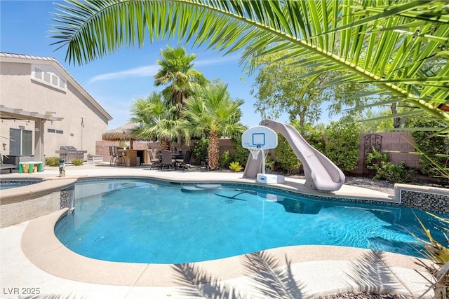 view of swimming pool featuring an in ground hot tub, a patio area, and a water slide