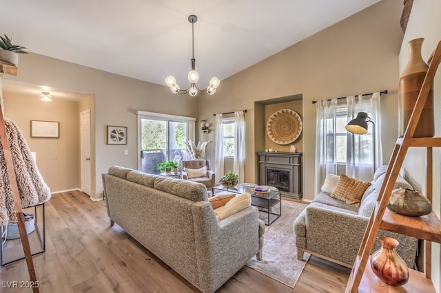 living room with a chandelier, light wood-type flooring, and lofted ceiling