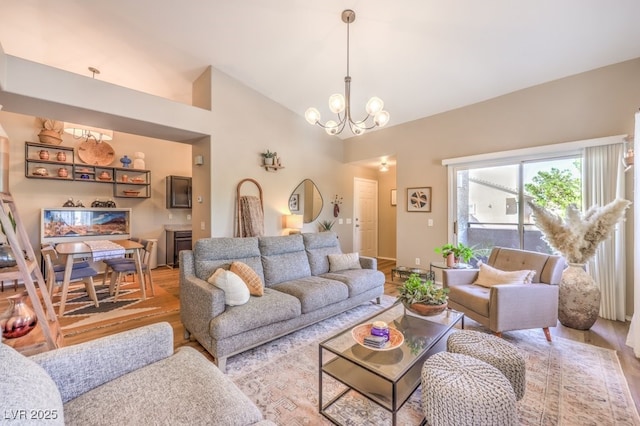 living room with light hardwood / wood-style flooring, an inviting chandelier, and lofted ceiling