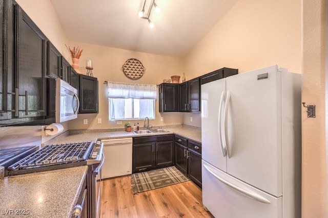 kitchen with light wood-type flooring, rail lighting, white appliances, sink, and lofted ceiling