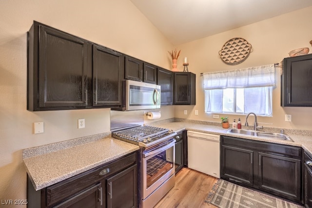 kitchen with sink, light hardwood / wood-style floors, lofted ceiling, and appliances with stainless steel finishes