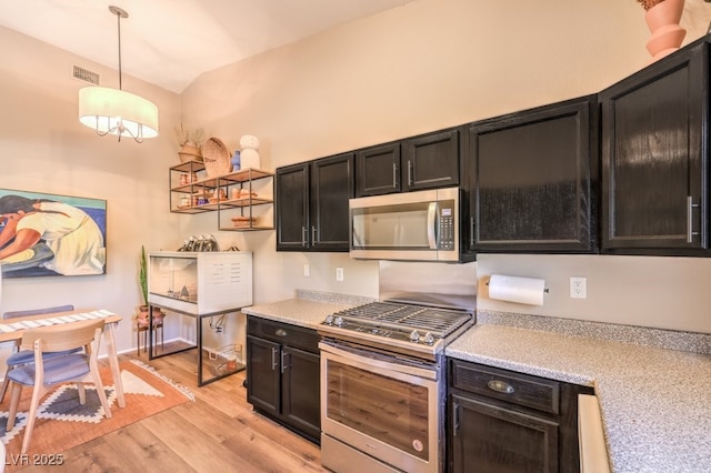 kitchen with appliances with stainless steel finishes, decorative light fixtures, vaulted ceiling, and light hardwood / wood-style floors