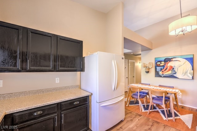 kitchen featuring pendant lighting, white fridge, and light wood-type flooring