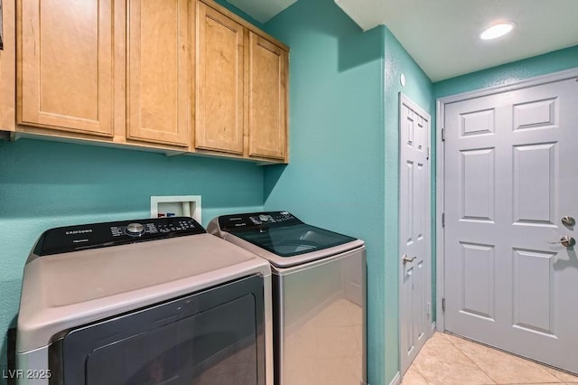 laundry area with washing machine and dryer, light tile patterned flooring, and cabinets