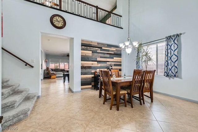 tiled dining area featuring ceiling fan with notable chandelier, a healthy amount of sunlight, and a high ceiling