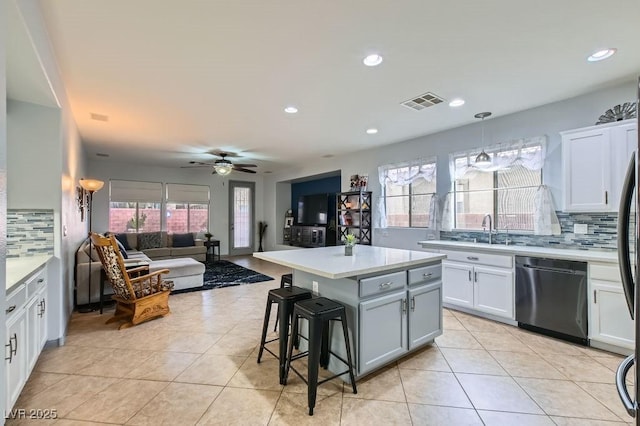 kitchen featuring stainless steel dishwasher, a kitchen island, white cabinetry, and tasteful backsplash