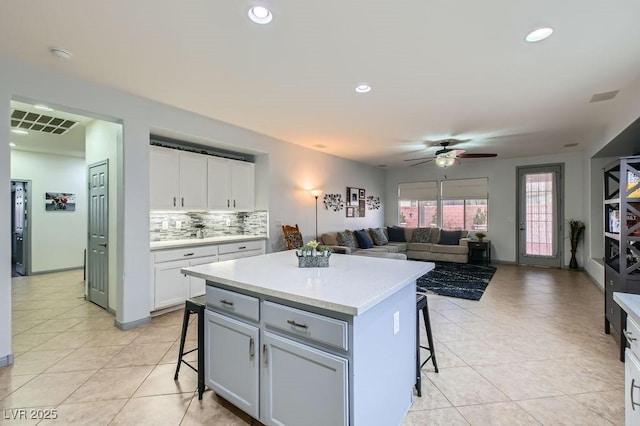 kitchen featuring a kitchen breakfast bar, white cabinetry, a center island, and ceiling fan