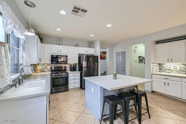 kitchen with white cabinets, black fridge, stainless steel range with gas cooktop, sink, and hanging light fixtures