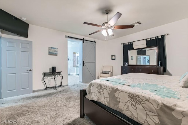 carpeted bedroom featuring ceiling fan, a barn door, and ensuite bath