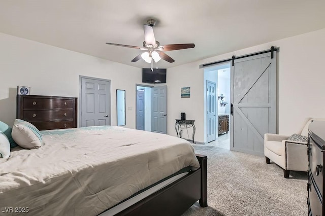 carpeted bedroom with a barn door, ceiling fan, and connected bathroom