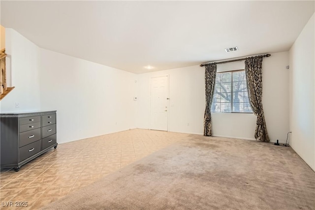 empty room featuring light tile patterned floors, visible vents, and light colored carpet