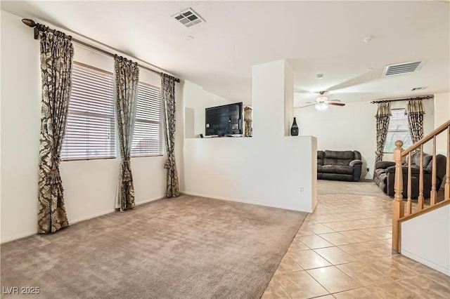 empty room with a wealth of natural light, light colored carpet, and visible vents