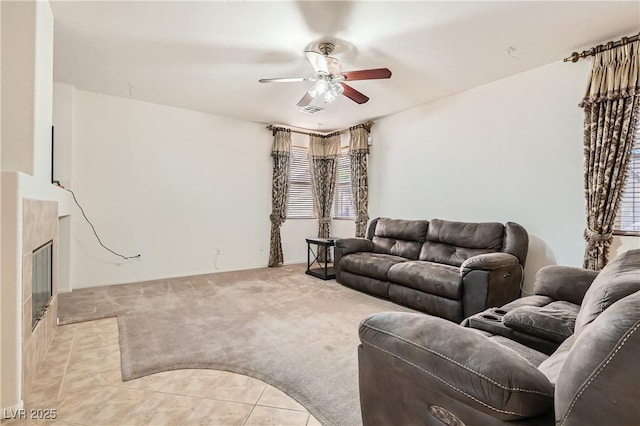 living area featuring ceiling fan, a fireplace, visible vents, and light colored carpet