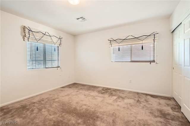 spare room featuring carpet, visible vents, and baseboards