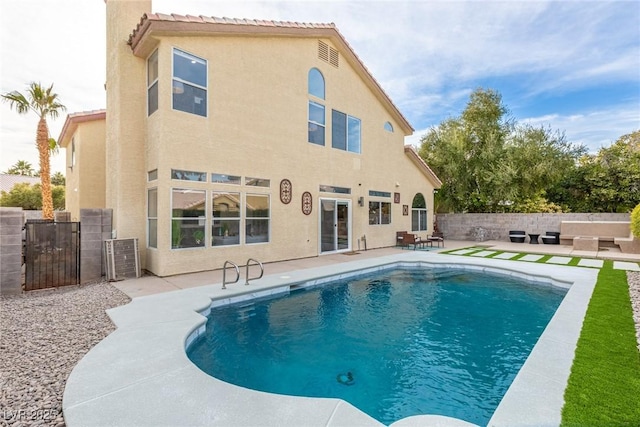 rear view of house with a fenced in pool and a patio area