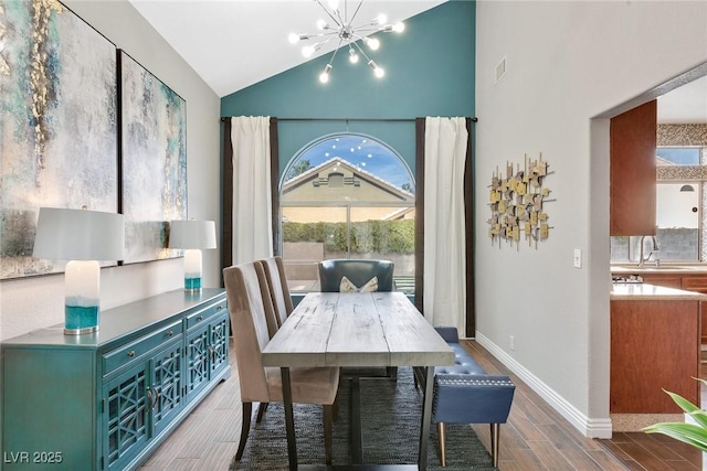 dining space with vaulted ceiling, an inviting chandelier, and sink